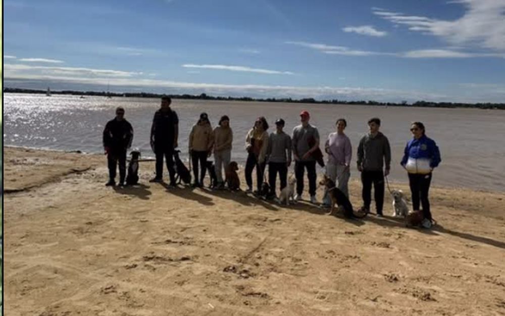 Clase grupal de Del Arrabal a orillas del río Paraná: alumnos con sus perros sentados y en calma