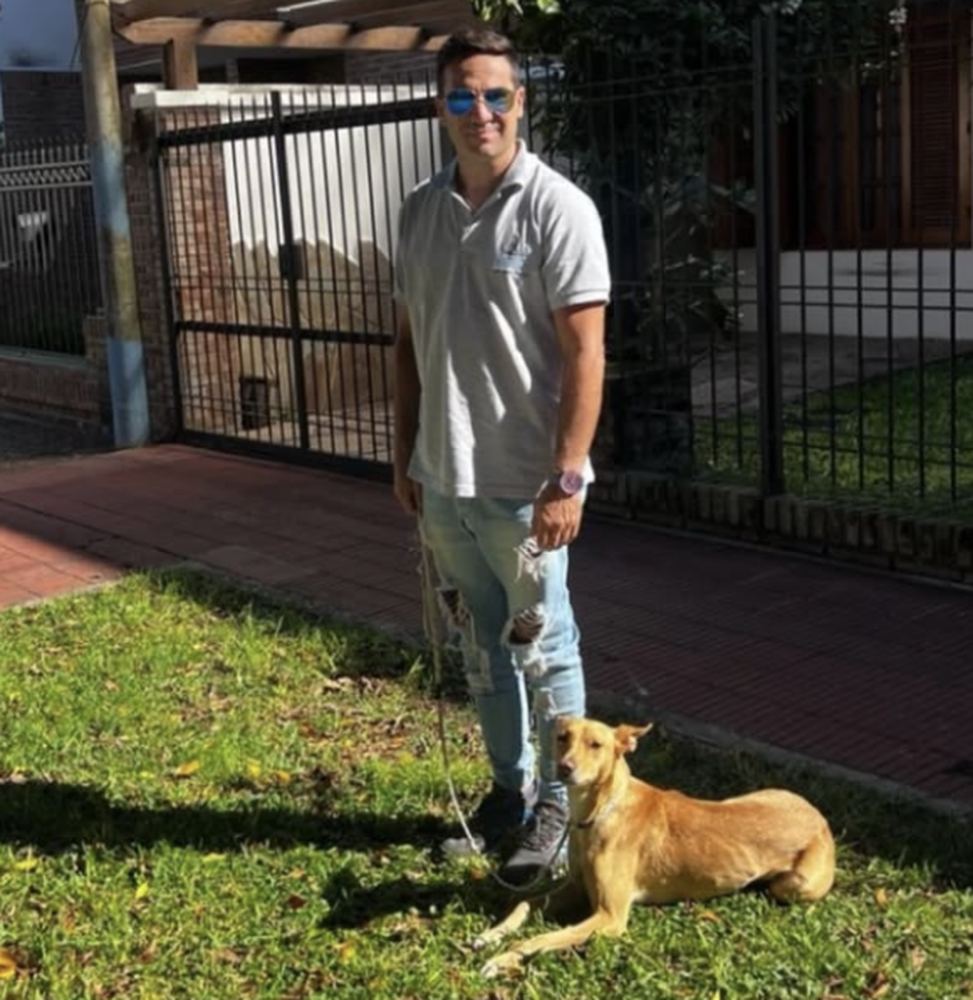 Adiestrador de Del Arrabal con un perro echado y tranquilo en el jardín de un cliente