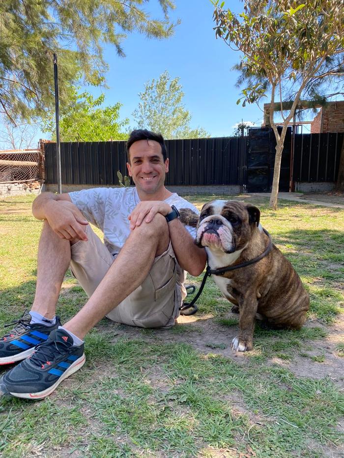 Adiestrador de Del Arrabal sentado en el pasto junto a un bulldog tranquilo en la escuela